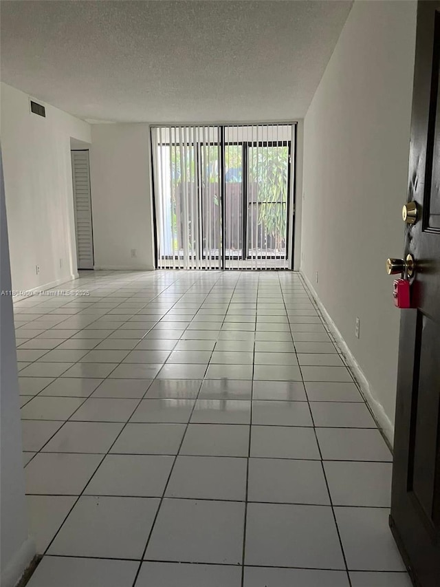 213 Lake Pointe Dr Unit 112, Oakland Park, FL 33309 - spare room with tile patterned flooring, a textured ceiling, floor to ceiling windows, and baseboards