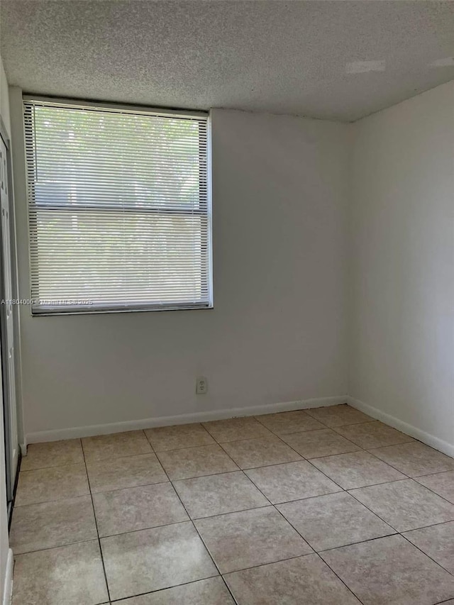 213 Lake Pointe Dr Unit 112, Oakland Park, FL 33309 - empty room with a textured ceiling, light tile patterned floors, plenty of natural light, and baseboards