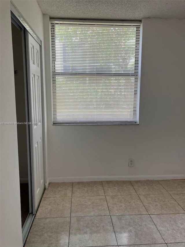 213 Lake Pointe Dr Unit 112, Oakland Park, FL 33309 - unfurnished dining area with a textured ceiling, light tile patterned floors, baseboards, and healthy amount of natural light