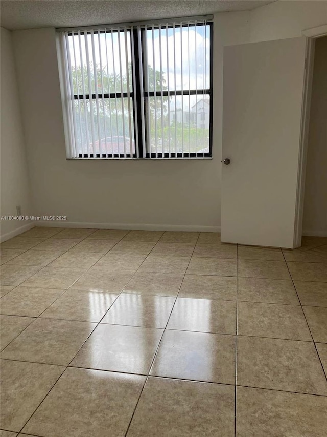 213 Lake Pointe Dr Unit 112, Oakland Park, FL 33309 - tiled empty room featuring healthy amount of natural light, baseboards, and a textured ceiling