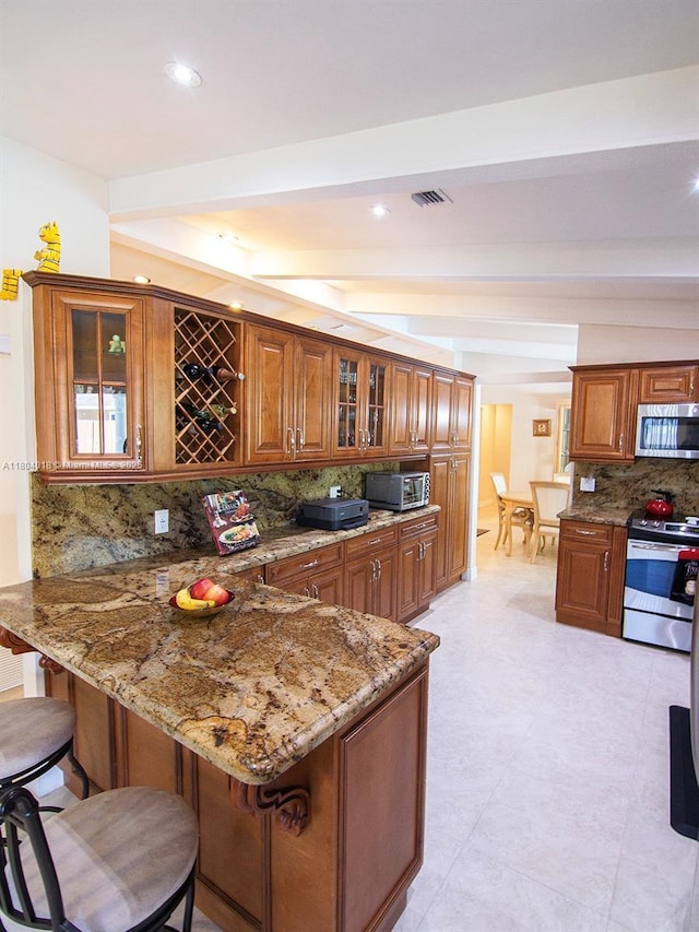 10715 SW 139th Ct, Miami, FL 33186 - kitchen featuring stainless steel appliances, brown cabinets, a kitchen breakfast bar, light stone counters, and decorative backsplash