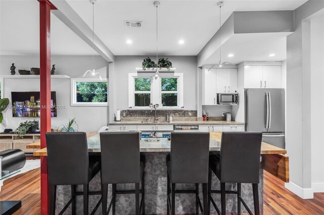 1631 SW 11th St, Miami, FL 33135 - kitchen featuring appliances with stainless steel finishes, a kitchen breakfast bar, a sink, white cabinets, and wood finished floors