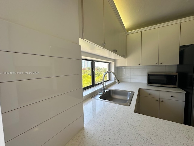 16919 N Bay Rd Unit 617, Sunny Isles Beach, FL 33160 - kitchen featuring stainless steel microwave, a sink, light countertops, tasteful backsplash, and freestanding refrigerator
