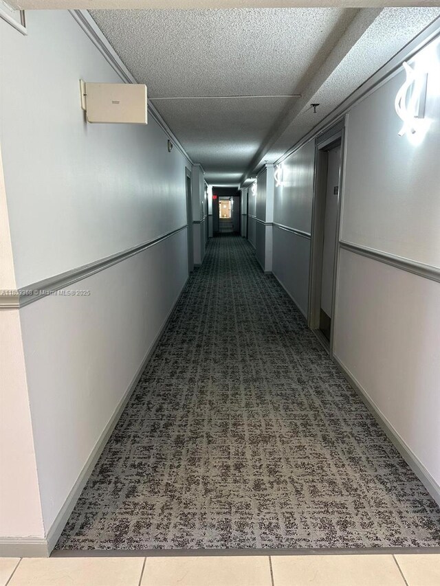 16919 N Bay Rd Unit 617, Sunny Isles Beach, FL 33160 - hall with dark colored carpet, a textured ceiling, and baseboards