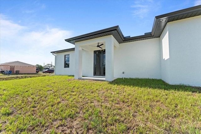 4623 7th St W, Lehigh Acres, FL 33971 - back of house featuring stucco siding, a yard, and a ceiling fan