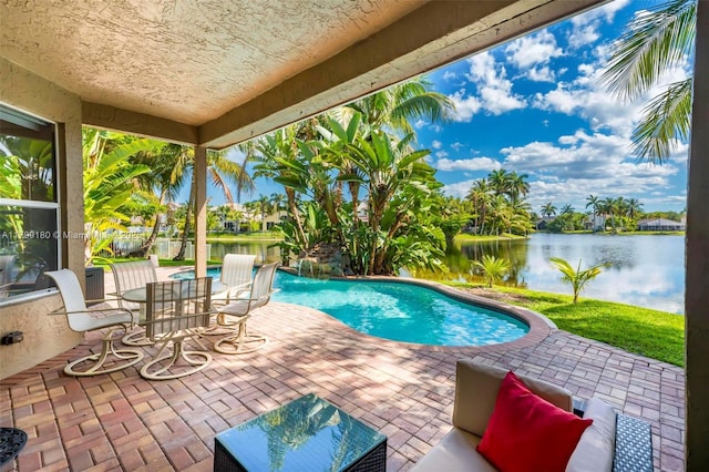 outdoor pool with a water view and a patio area