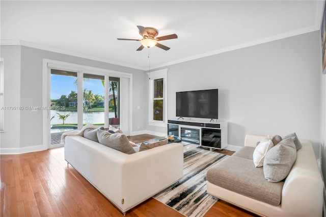 living room with a ceiling fan, baseboards, ornamental molding, and light wood-type flooring
