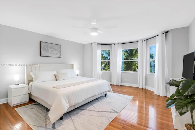 bedroom featuring light wood-type flooring, baseboards, and a ceiling fan
