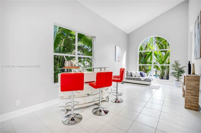 dining space with vaulted ceiling, baseboards, and tile patterned flooring