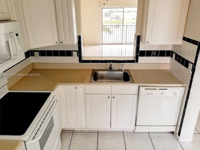 kitchen featuring white appliances, a sink, white cabinets, and decorative backsplash