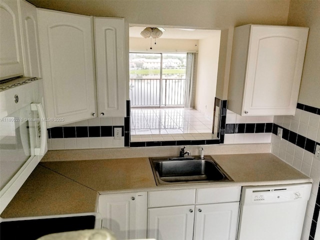 kitchen with white dishwasher, a sink, white cabinetry, and a ceiling fan