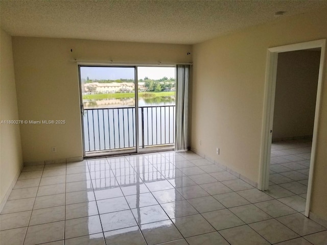 empty room featuring a water view, light tile patterned floors, and a textured ceiling