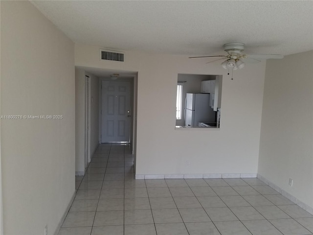 empty room featuring light tile patterned floors, a ceiling fan, and baseboards