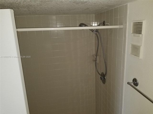 bathroom featuring a tile shower and a textured ceiling