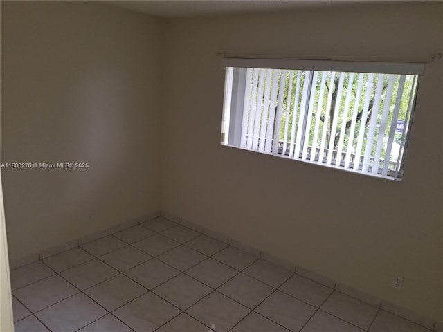 spare room featuring light tile patterned floors and baseboards