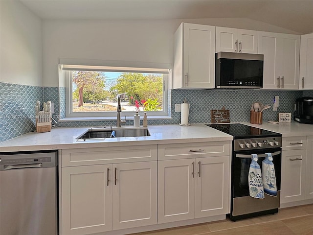 32 Pirates Dr, Key Largo, FL 33037 - kitchen with stainless steel appliances, a sink, white cabinets, backsplash, and vaulted ceiling
