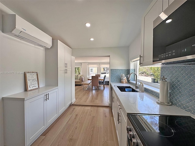 32 Pirates Dr, Key Largo, FL 33037 - kitchen with a sink, appliances with stainless steel finishes, a wall mounted AC, light wood-style floors, and white cabinets