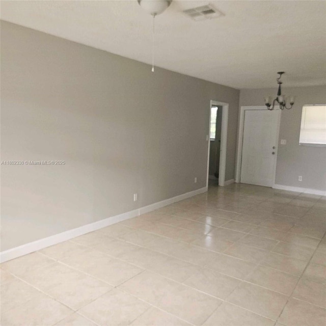 spare room featuring light tile patterned flooring, a chandelier, and baseboards
