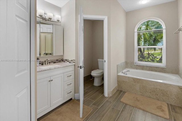112 SW N Danville Cir, Port St Lucie, FL 34953 - bathroom featuring toilet, a bath, vanity, wood finished floors, and decorative backsplash