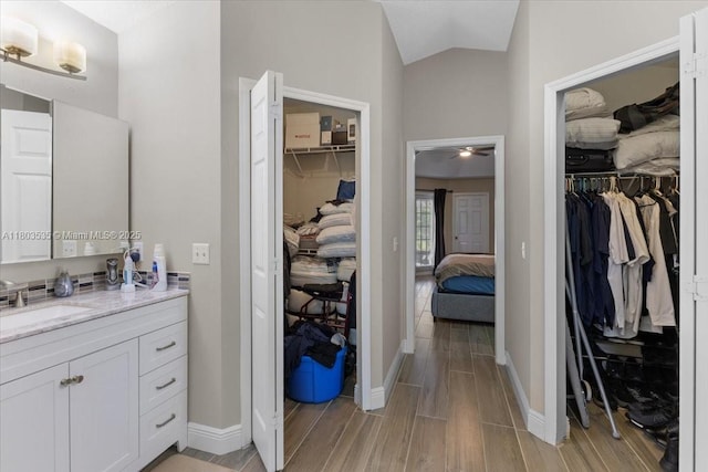 112 SW N Danville Cir, Port St Lucie, FL 34953 - bathroom featuring wood finished floors, vanity, a walk in closet, and lofted ceiling