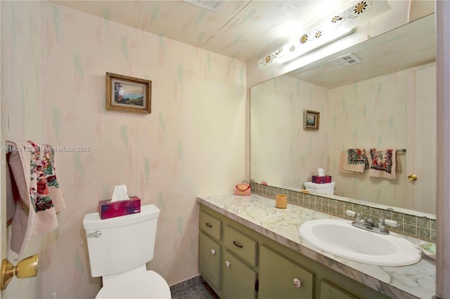 bathroom featuring vanity, toilet, and wallpapered walls