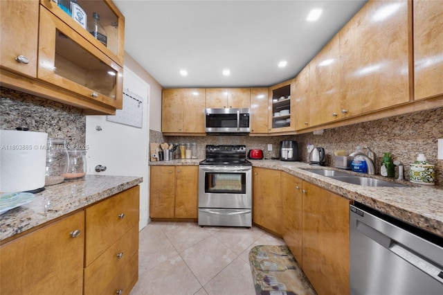 400 Kings Point Dr Unit 1021, Sunny Isles Beach, FL 33160 - kitchen with stainless steel appliances, a sink, decorative backsplash, light tile patterned flooring, and glass insert cabinets