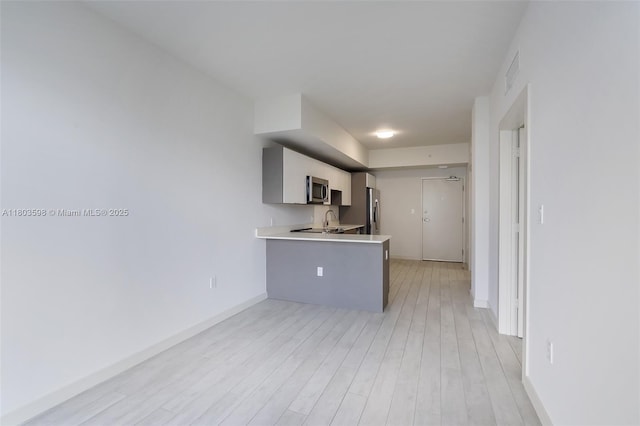 321 NE 26th St Unit 614, Miami, FL 33137 - kitchen featuring stainless steel appliances, light countertops, light wood-style flooring, and a peninsula
