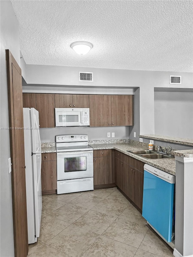 kitchen featuring white appliances, a textured ceiling, a sink, light tile patterned floors, and light countertops