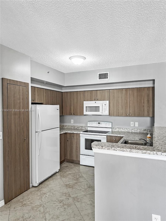 kitchen with white appliances, a peninsula, a textured ceiling, a sink, and light tile patterned flooring