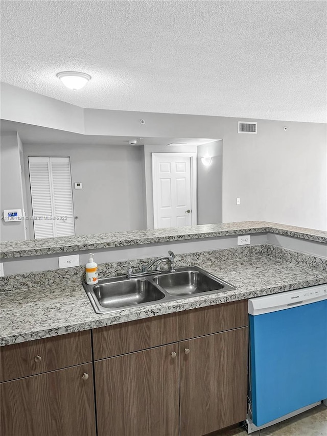 kitchen featuring dishwashing machine, a textured ceiling, a sink, and light countertops