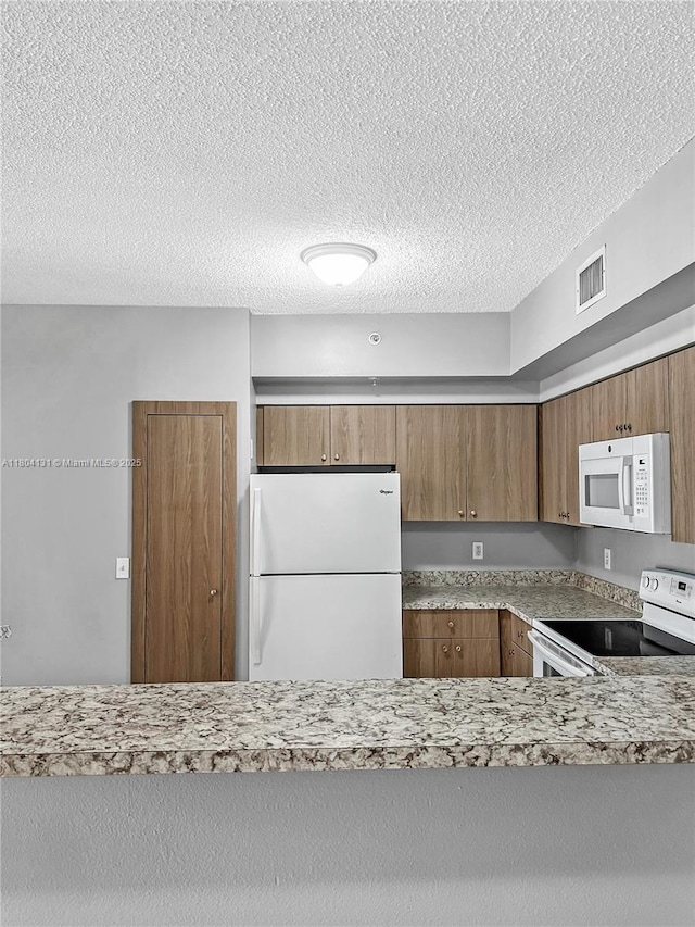 2240 E Preserve Way Unit 205, Miramar, FL 33025 - kitchen with white appliances, a textured ceiling, and brown cabinetry
