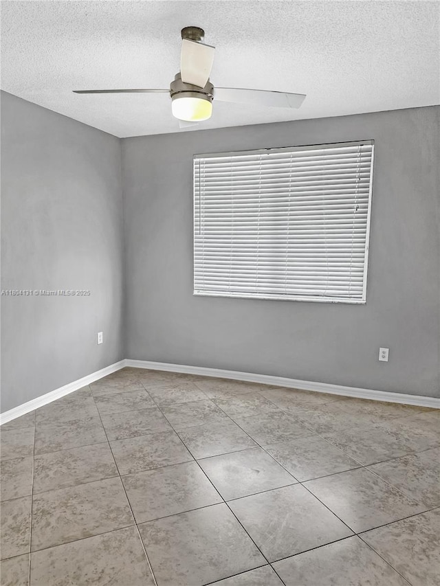 unfurnished room with a textured ceiling, tile patterned flooring, and baseboards