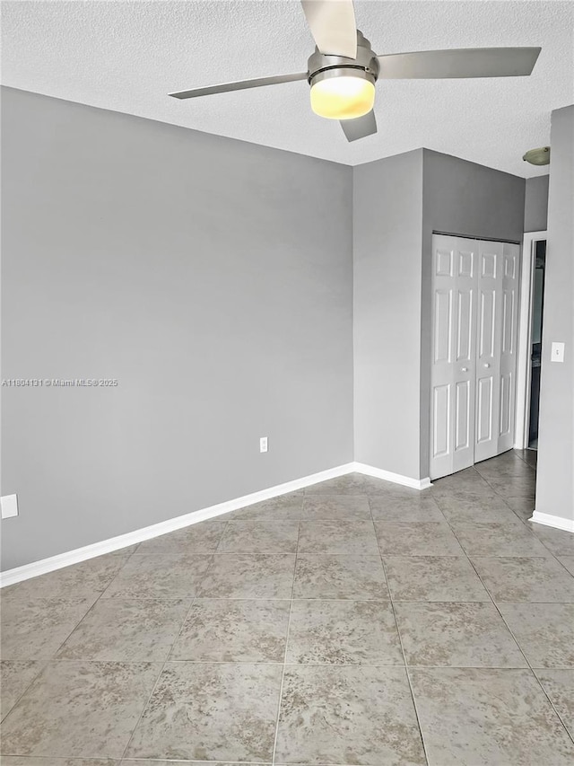 unfurnished room with a ceiling fan, a textured ceiling, and baseboards