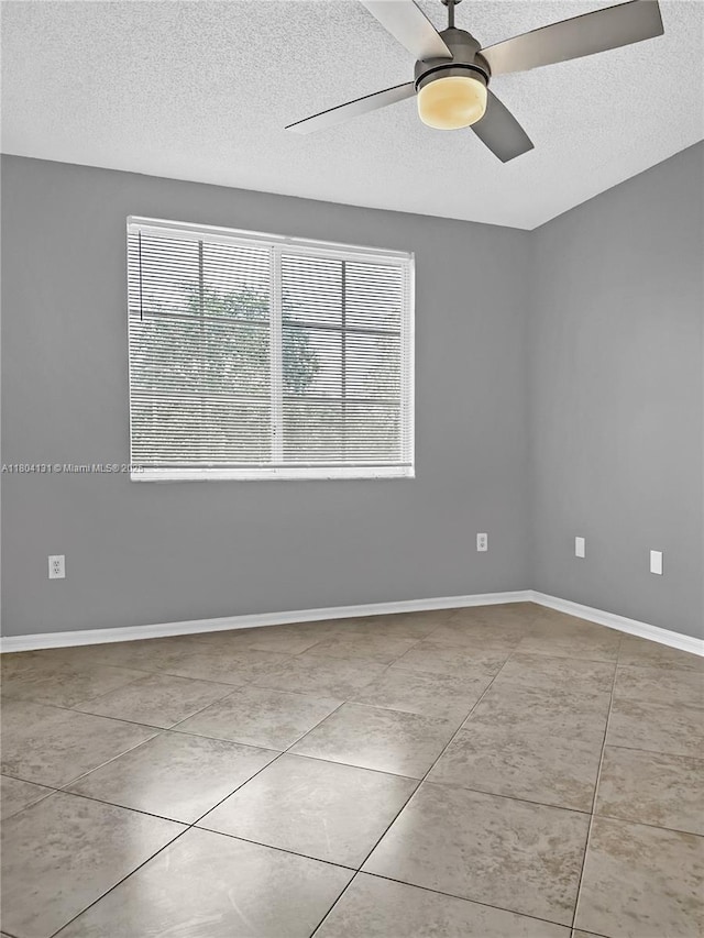 tiled spare room featuring a textured ceiling, a ceiling fan, and baseboards