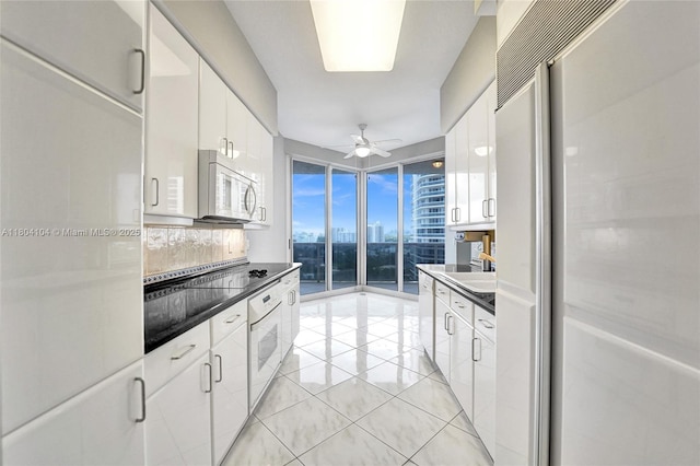 3200 N Ocean Blvd Unit 1206, Fort Lauderdale, FL 33308 - kitchen featuring white appliances, dark countertops, light tile patterned flooring, decorative backsplash, and white cabinetry
