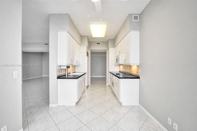 3200 N Ocean Blvd Unit 1206, Fort Lauderdale, FL 33308 - kitchen with dark countertops, light tile patterned floors, white cabinets, and a ceiling fan