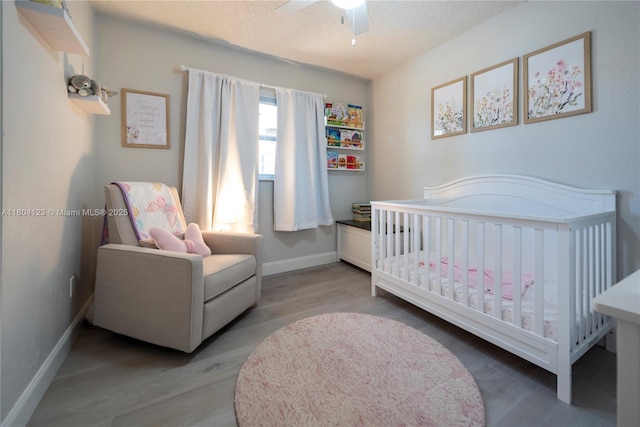 22226 SW 65th Ter, Boca Raton, FL 33428 - bedroom with a crib, wood finished floors, a textured ceiling, baseboards, and a ceiling fan