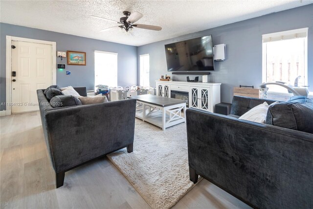22226 SW 65th Ter, Boca Raton, FL 33428 - living area with a ceiling fan, light wood-style floors, a textured ceiling, and a glass covered fireplace