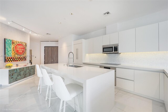 88 SW 7th St Unit 4101, Miami, FL 33130 - kitchen featuring stainless steel microwave, a sink, track lighting, and modern cabinets