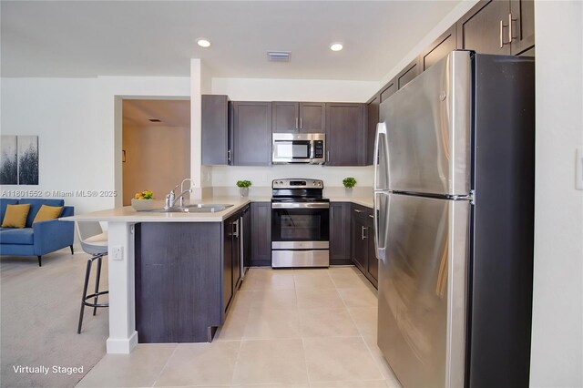 11094 W 33rd Way, Hialeah, FL 33018 - kitchen featuring appliances with stainless steel finishes, a sink, a peninsula, a breakfast bar area, and dark brown cabinets