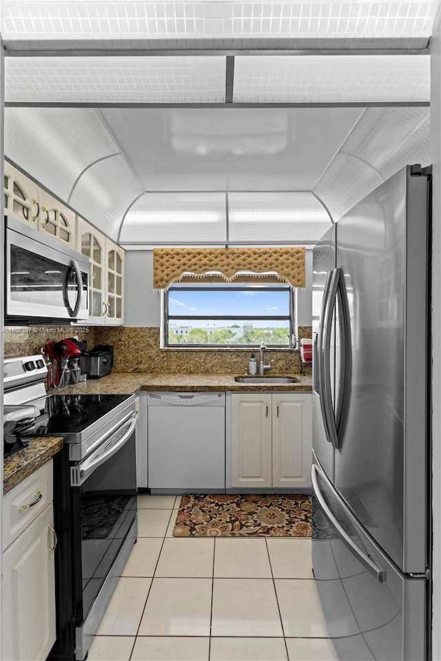 900 Colony Point Cir Unit 523, Pembroke Pines, FL 33026 - kitchen featuring appliances with stainless steel finishes, glass insert cabinets, light tile patterned floors, backsplash, and white cabinetry