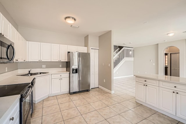 17668 SW 135th Ct, Miami, FL 33177 - kitchen featuring appliances with stainless steel finishes, arched walkways, light countertops, light tile patterned floors, and white cabinets