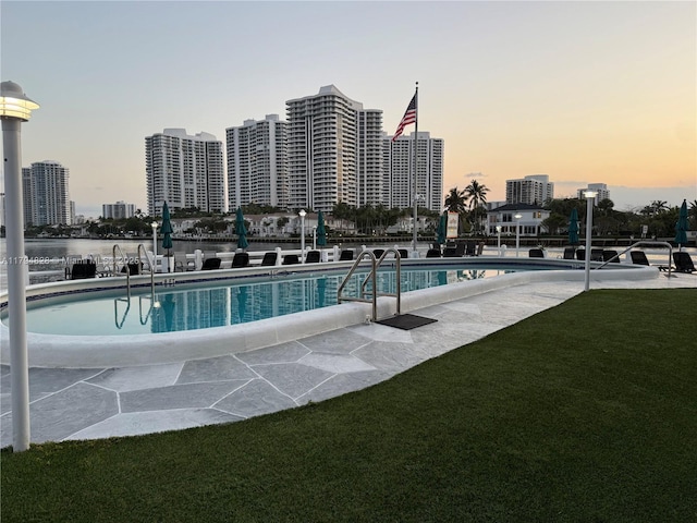 3209 S Ocean Dr Unit 2M, Hallandale Beach, FL 33009 - pool at dusk featuring a community pool, a yard, and a city view