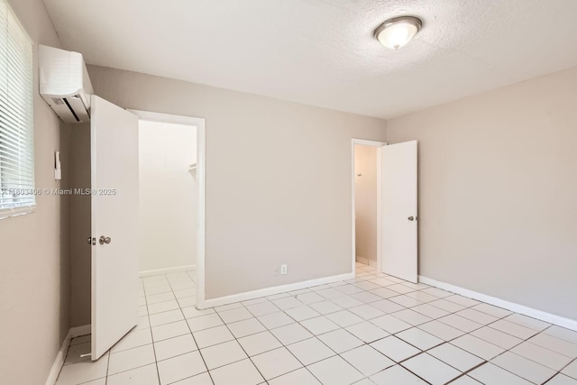 3226 NW 41st St, Lauderdale Lakes, FL 33309 - empty room with a wall mounted AC, a textured ceiling, light tile patterned flooring, and baseboards