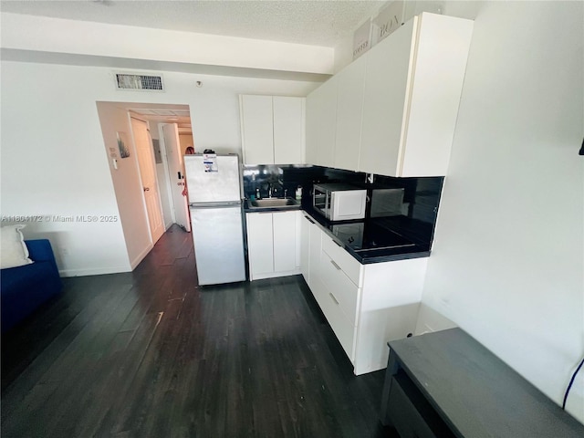 6345 Collins Ave Unit 818, Miami Beach, FL 33141 - kitchen featuring white appliances, dark countertops, dark wood-style floors, a sink, and white cabinetry