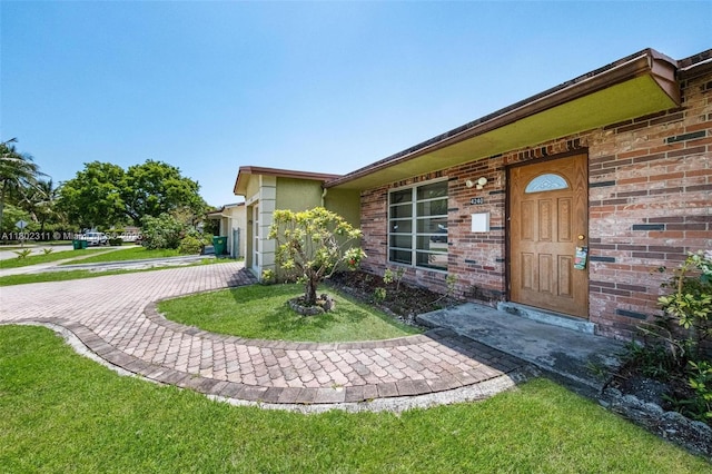 4240 NW 22nd St, Lauderhill, FL 33313 - view of exterior entry featuring brick siding and a lawn