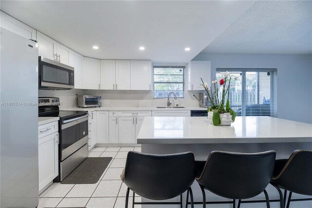 8693 SW 137th Ave Unit 8693, Miami, FL 33183 - kitchen with appliances with stainless steel finishes, a breakfast bar area, light countertops, light tile patterned floors, and white cabinetry