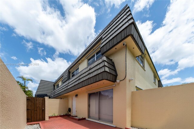 8693 SW 137th Ave Unit 8693, Miami, FL 33183 - back of house featuring stucco siding, a gate, a patio area, and mansard roof