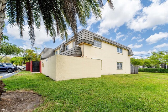 8693 SW 137th Ave Unit 8693, Miami, FL 33183 - view of home's exterior with mansard roof, a yard, and stucco siding