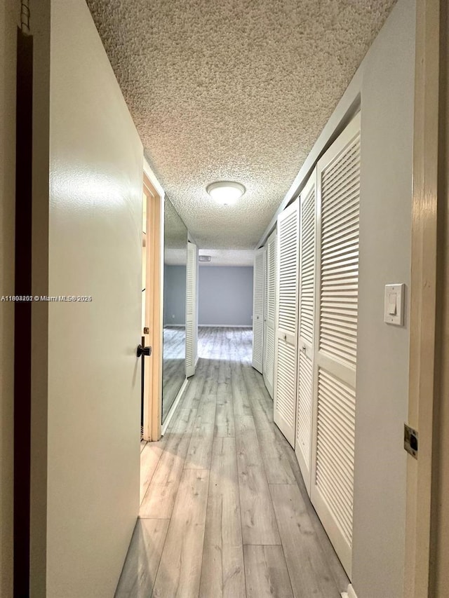 601 Ives Dairy Rd Unit 401-8, Miami, FL 33179 - hall featuring a textured ceiling and light wood-style floors